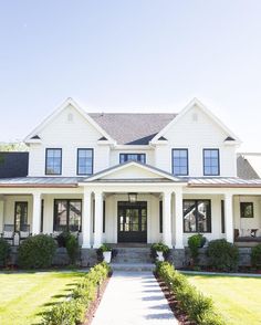 a large white house with lots of windows on the front and side of it's porch