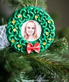 a christmas ornament hanging on a tree with a photo in the center and red bow