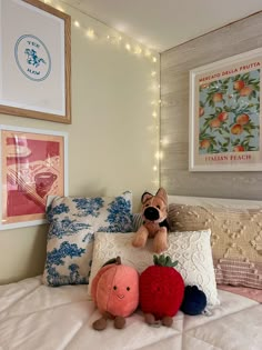 two stuffed animals sitting on top of a bed next to pillows and pictures above them