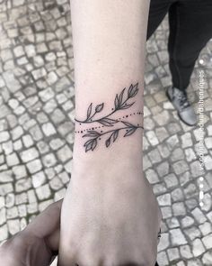 a woman's wrist tattoo with leaves on it