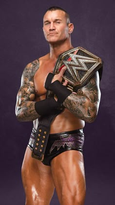 a man with tattoos holding a wrestling belt