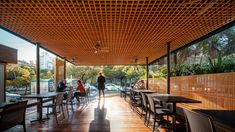 people are sitting at tables under an awning on the outside patio with wooden flooring