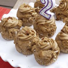 a white plate topped with cupcakes covered in frosting and a number two candle