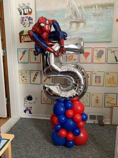 the number five balloon sculpture is in front of a wall decorated with pictures and balloons