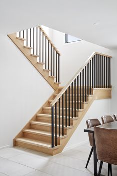 a dining room table and some chairs under a stair case next to a wooden banister