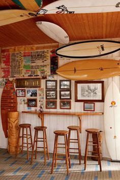 a surfboard is hanging from the ceiling in a room with stools and tables