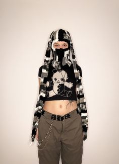 a woman wearing a black and white hoodie with chains on her belt is standing in front of a wall