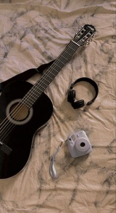 an acoustic guitar and headphones on a bed