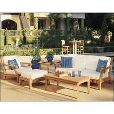 an outdoor living room with white couches and blue pillows