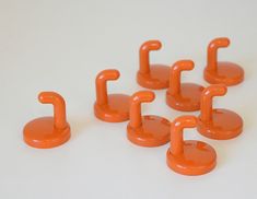 an orange set of six umbrella hooks on a white surface