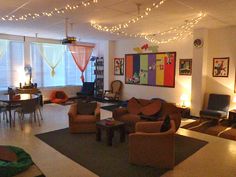 a living room filled with lots of furniture and lights hanging from the ceiling above it