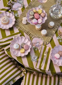 a table topped with plates and cups filled with desserts on top of striped napkins