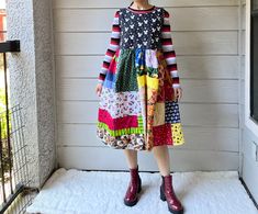 a woman standing in front of a door wearing a dress made out of patchwork