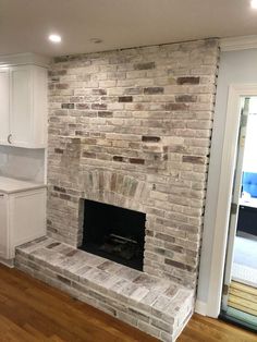 an empty living room with white cabinets and a brick fireplace in the middle of it