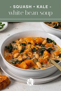 a white bowl filled with chicken and spinach soup on top of a table next to bread