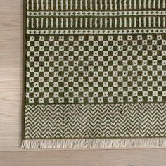 a green and white rug on top of a wooden floor