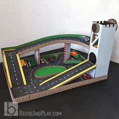 a toy train set with cars and trucks on the tracks in front of a white wall