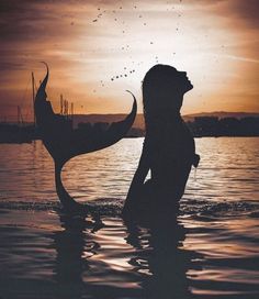 a woman standing in the water next to a bird