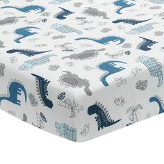 a blue and white crib sheet with dinosaurs on it, in front of a white background