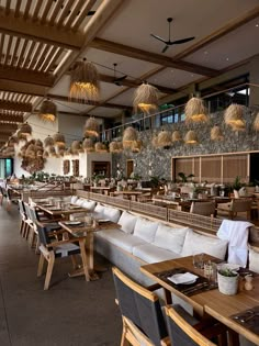 a restaurant with wooden tables and white couches in front of a large stone wall