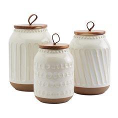 three white ceramic jars with wooden lids