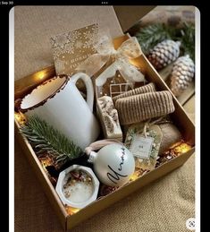 an open box filled with christmas items on top of a table next to pine cones