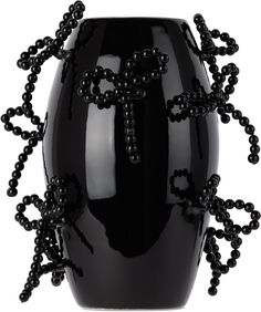 a black vase with beads on it and a cross in the middle, as well as other decorations