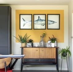 a living room with yellow walls and pictures on the wall