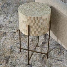 a round wooden table sitting on top of a rug next to a couch and chair