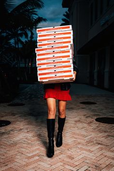 a woman walking down the street with a box on her head in front of her