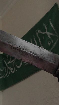 a close up of a knife with writing on the wall in front of a flag