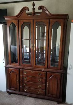 a large wooden china cabinet with glass doors