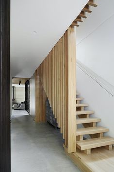 a wooden stair case next to a white wall