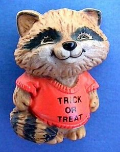 a raccoon figurine with a trick or treat shirt on