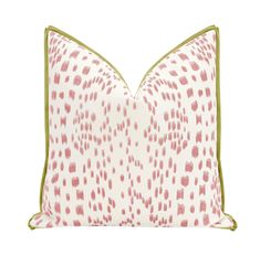 a pink and white pillow with green piping on the front, sitting on a white surface