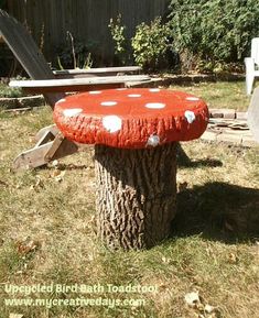 a tree stump with a red and white mushroom sitting on it's side in the yard