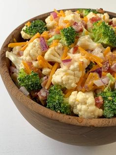 a wooden bowl filled with broccoli and cheese