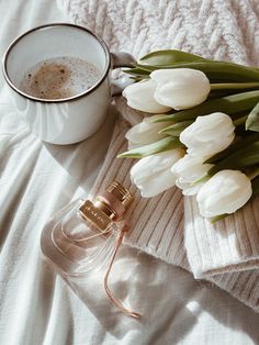 white tulips and a cup of coffee on a bed