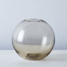 a clear glass vase sitting on top of a white tablecloth covered floor next to a wall