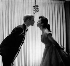 a man and woman kissing in front of curtains