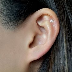 a woman's ear with two small white stars on the side of her ear