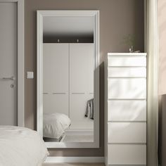 a bedroom with a white dresser and mirror