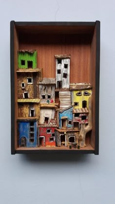 a wooden box that has some small houses in it on the side of a wall