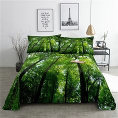 a bed with green trees on it and pictures above the bedspread, in a white room