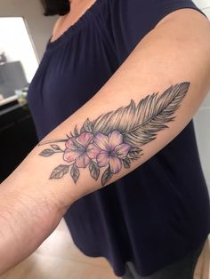 a woman with a flower and feather tattoo on her arm