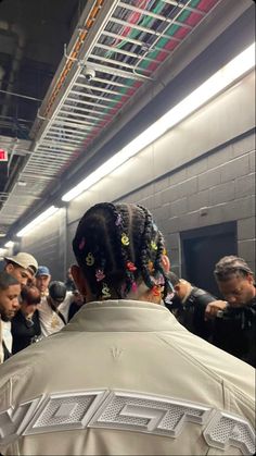 a group of people standing around each other in a subway station with one person wearing a white jacket