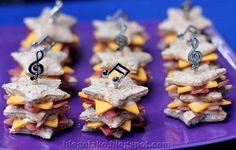 small sandwiches with cheese, meat and music notes on them sitting on a purple plate