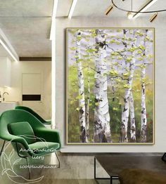 a painting hanging on the wall above a green chair in front of a white tree