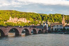 an old bridge spanning the width of a river with buildings on both sides and hills in the background