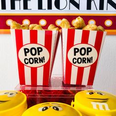 two popcorn bags with faces drawn on them sitting in front of some movie popcorns